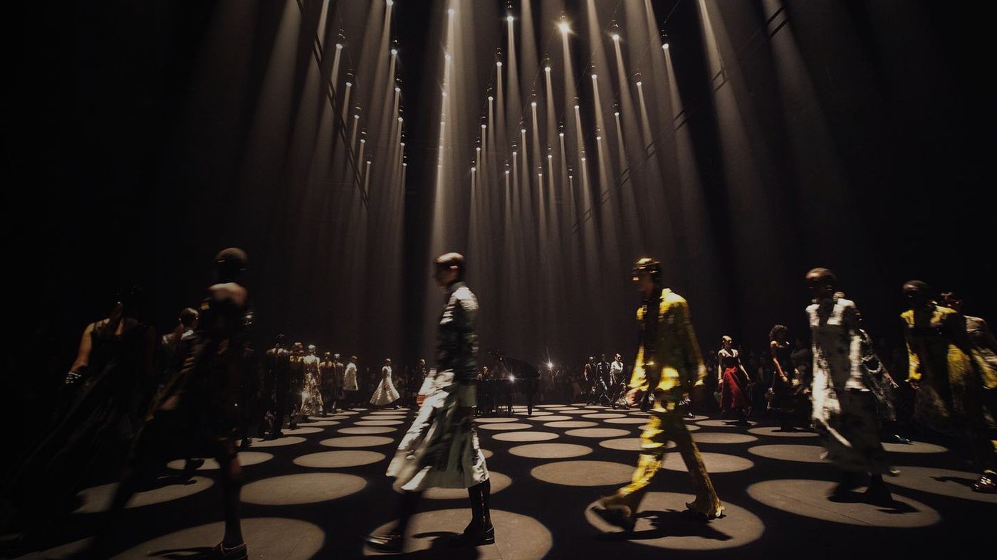Models walking a runway at London Fashion Week lit from above